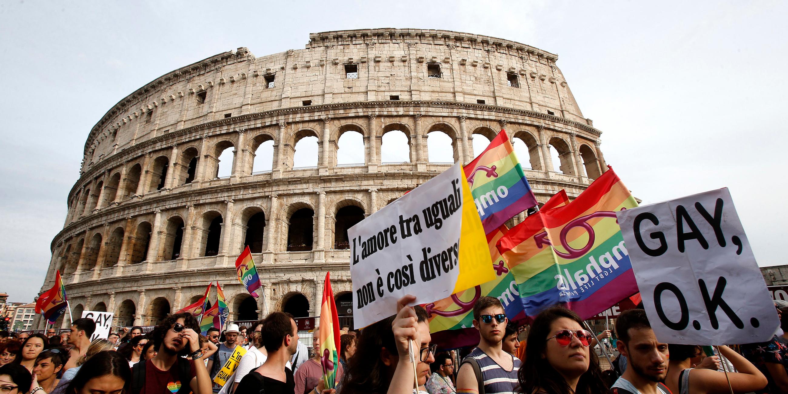 Vor dem Kolloseum demonstrieren Menschen mit Regenbogenflaggen.