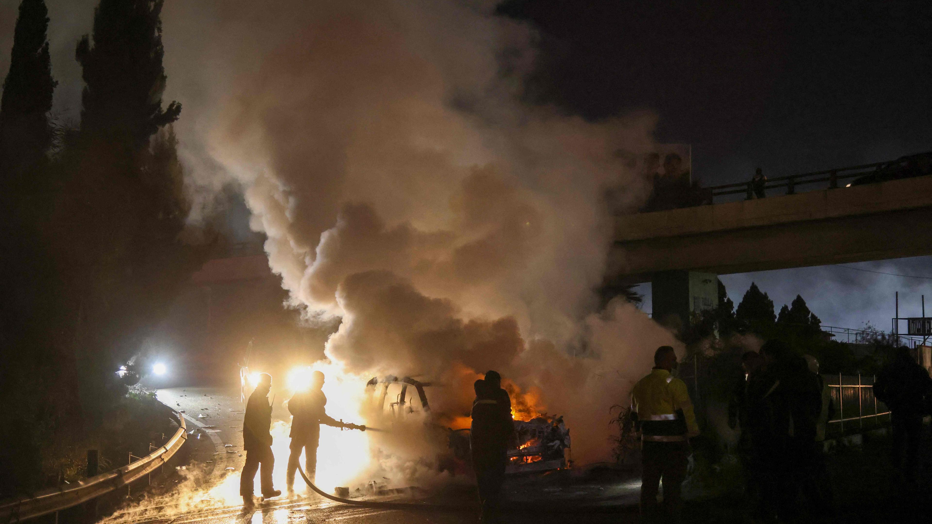 Feuerwehrleute löschen am 14. Februar 2025 auf der Straße zum internationalen Flughafen von Beirut ein brennendes UNIFIL-Fahrzeug, das von Demonstranten in Brand gesteckt wurde.