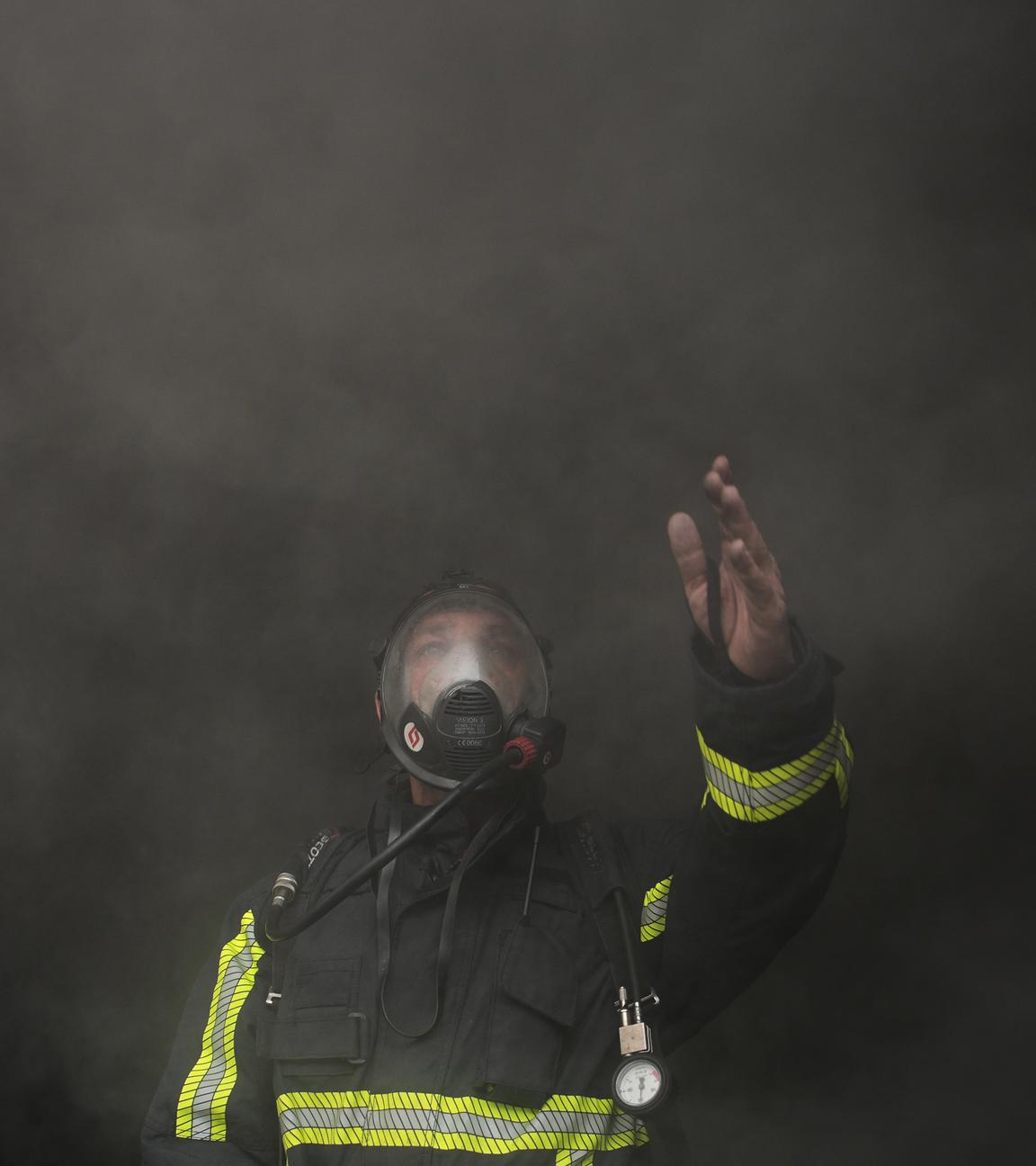 Ein Feuerwehrmann in Beirut, Libanon, winkt um Hilfe, während er sich durch dichten Rauch bewegt.