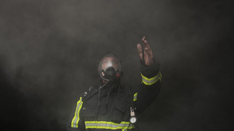 Ein Feuerwehrmann in Beirut, Libanon, winkt um Hilfe, während er sich durch dichten Rauch bewegt.