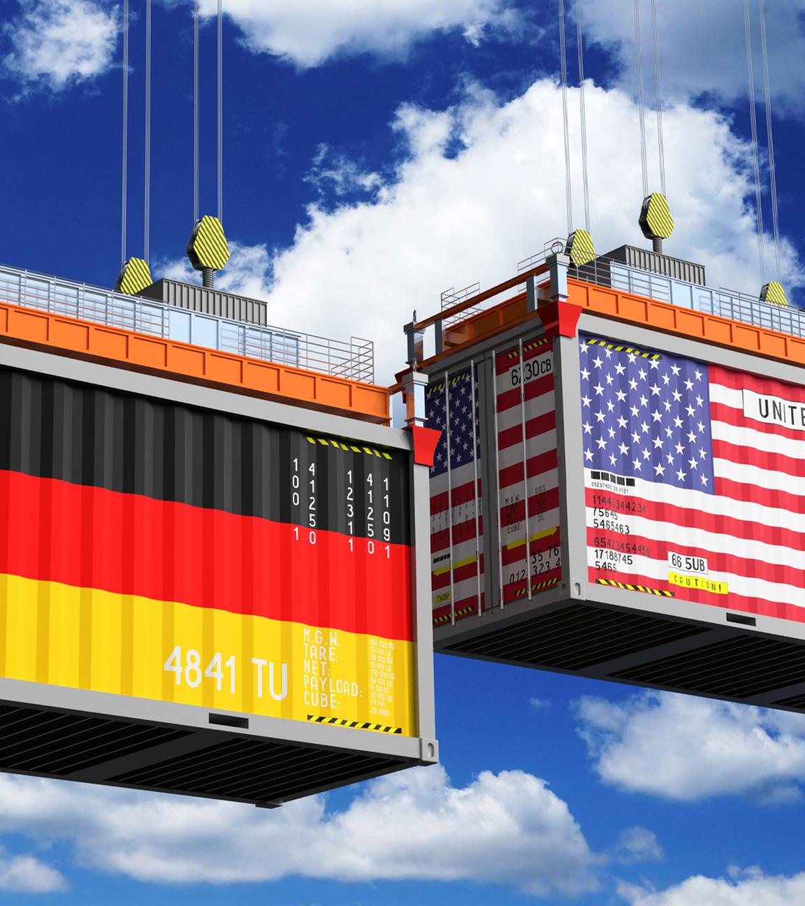Zwei große Frachtcontainer werden von Kränen vor einem blauen Himmel mit Wolken angehoben. Der linke Container trägt die deutsche Flagge und die Aufschrift „Germany“, der rechte die US-Flagge und „United States of America“. Die Darstellung symbolisiert den transatlantischen Handel und Spannungen durch Zölle, die Warenströme beeinflussen.