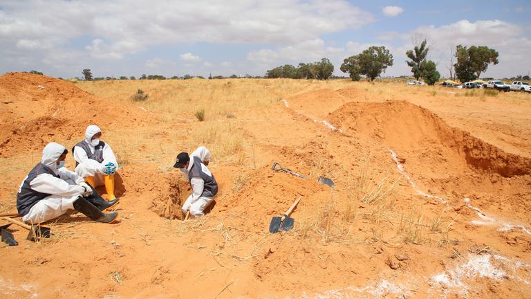Mitarbeiter des libyschen Justizministeriums nehmen an Grabungen an einer Stelle teil, an der sich mutmaßlich ein Massengrab befindet.