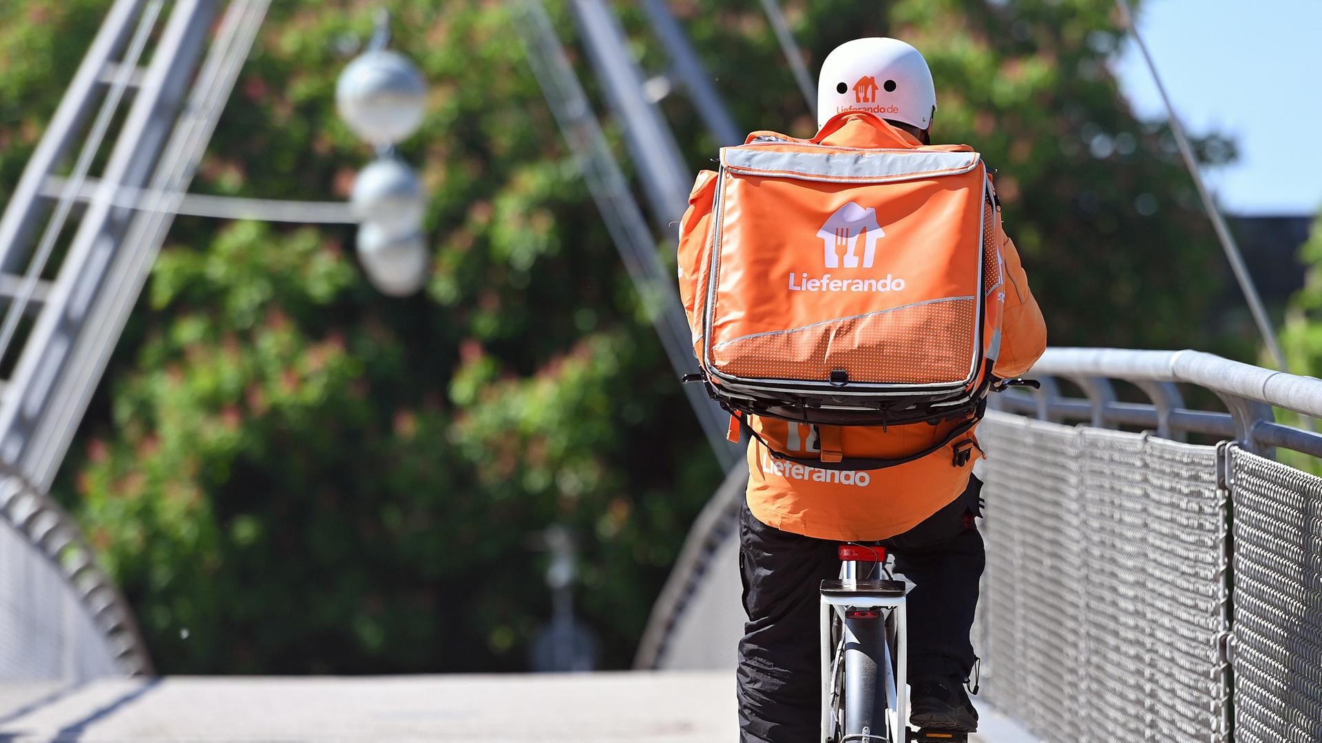 Lieferando-Fahrer überquert eine Brücke mit seinem Fahrrad. (Archiv)