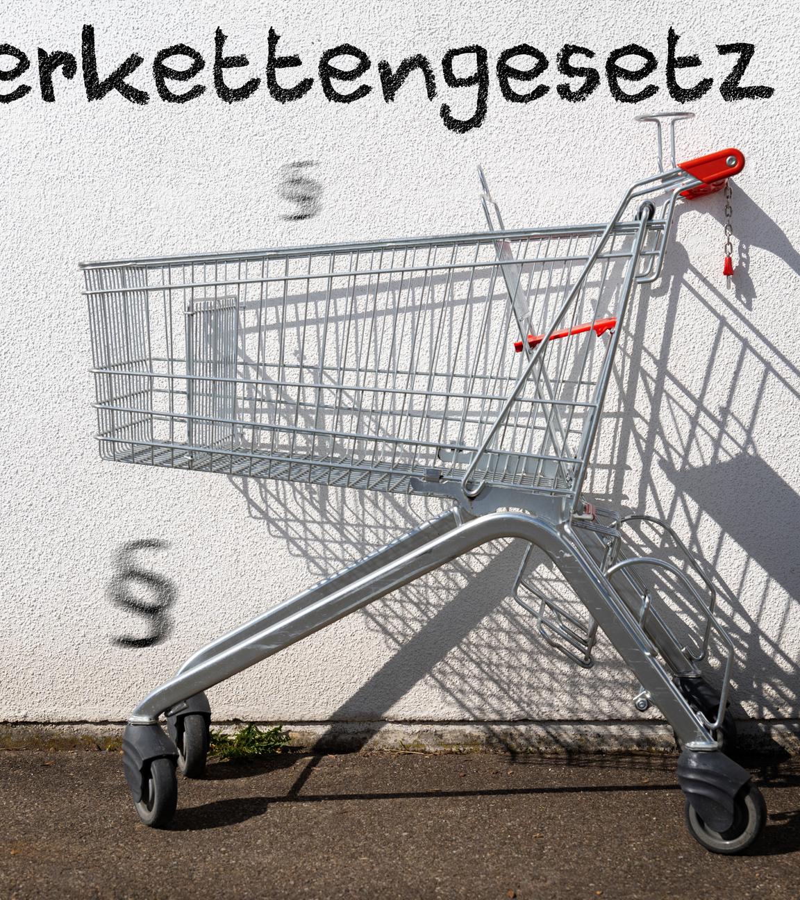 Leerer Einkaufswagen an einer Wand mit Aufschrift: Lieferkettengesetz.