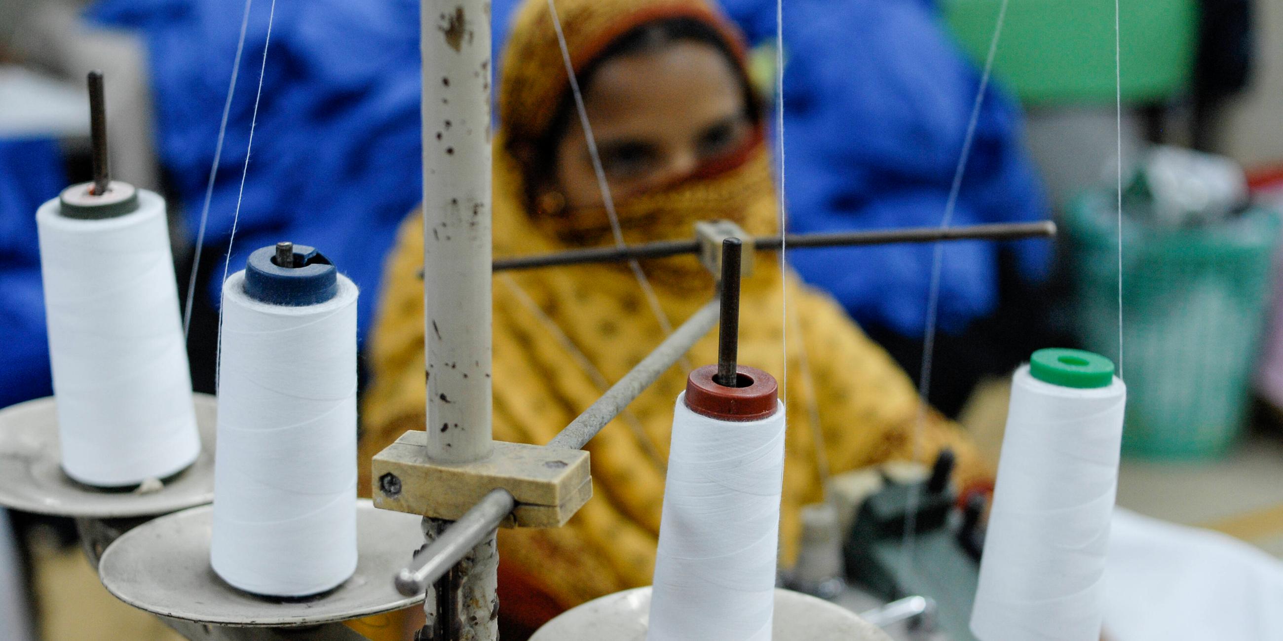 Eine unscharf fotografierte Näherin in einer Textilfabrik in Bangladesch.