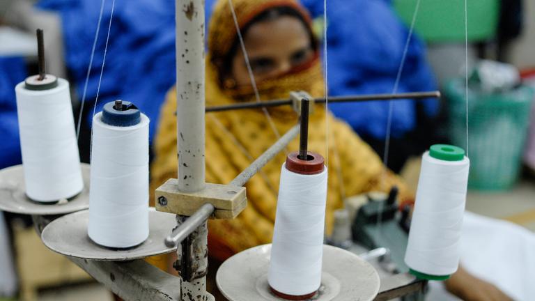 Eine unscharf fotografierte Näherin in einer Textilfabrik in Bangladesch.