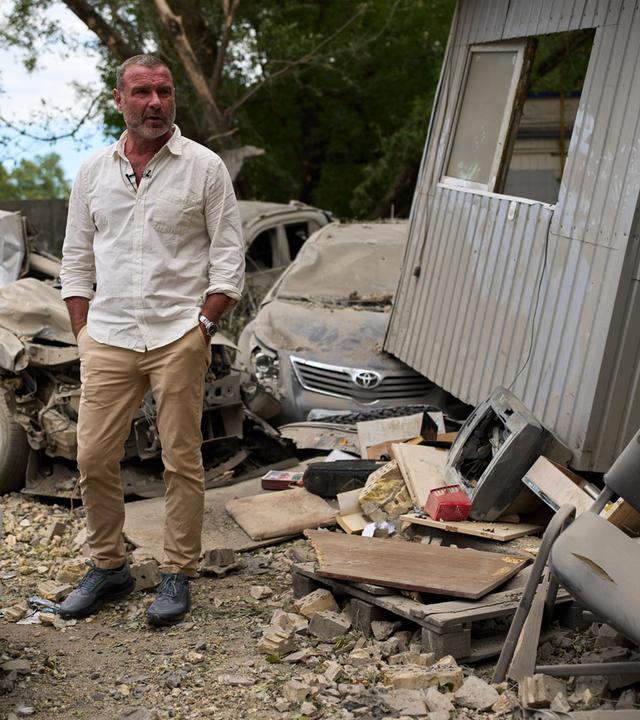 Auf dem Bild zu sehen ist: Schauspieler Liev Schreiber in einer Halbtotalen umgeben von Trümern des russichen Angriff Krieges.