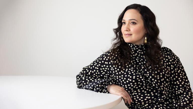 Die Schauspielerin sitzt an einem Tisch und lächelt