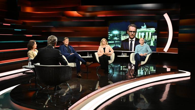 Carsten Linnemann ist bei Lanz im Anzug auf einem Bildschirm zu sehen. Im Vordergrund sitzen weitere Gäste von Markus Lanz.