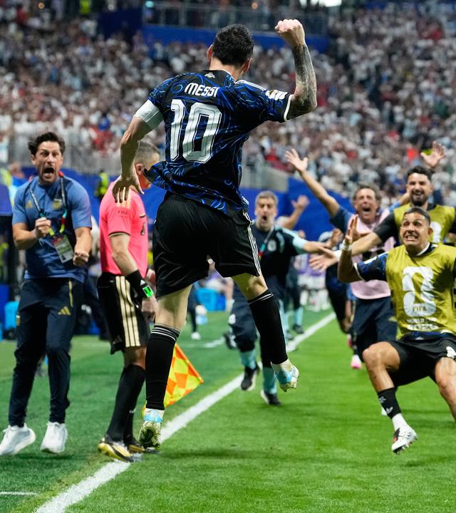 Der argentinische Nationalspieler Lionel Messi springt jubelnd in die Luft, während seine Teamkollegen jubelnd auf ihn zurennen
