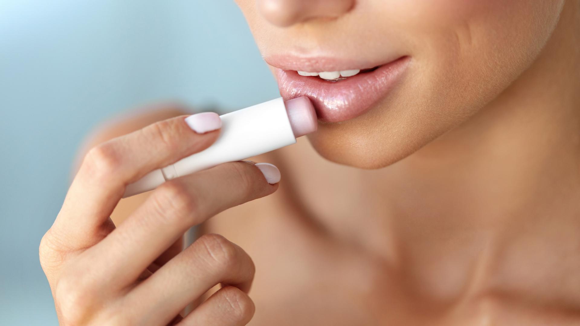 Eine junge Frau trägt einen Lippenpflegestift auf.