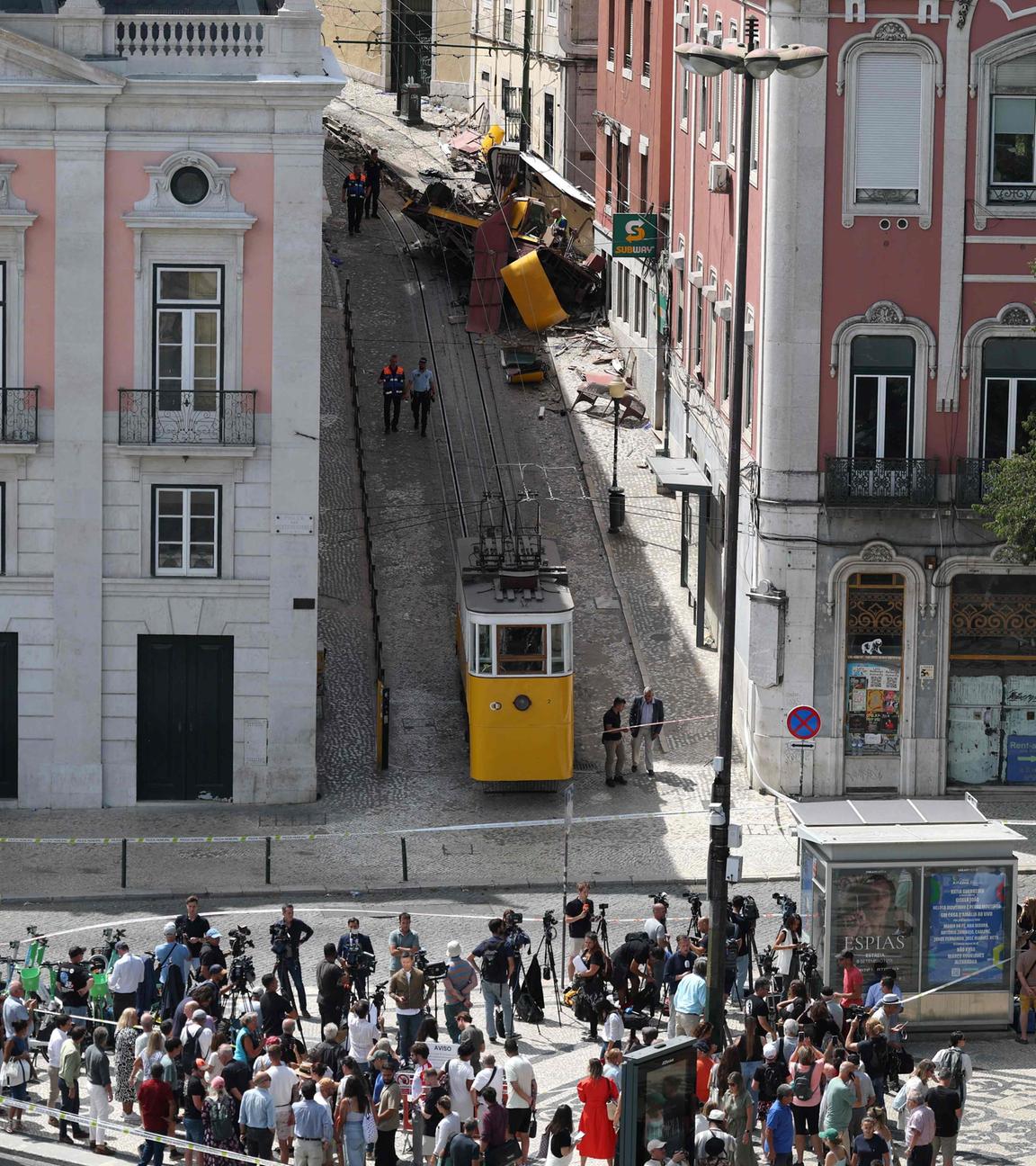 Lissabon, Portugal: Menschen versammeln sich vor der Unfallstelle. Im Hintergrund ist die entgleiste Standseilbahn.