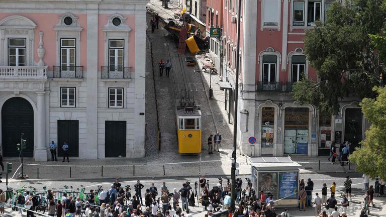 Lissabon, Portugal: Menschen versammeln sich vor der Unfallstelle. Im Hintergrund ist die entgleiste Standseilbahn.