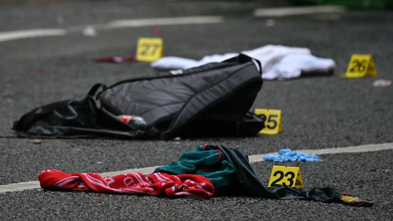Police forensics identification numbers are pictured among discarded belongings at the scene on Water Street in Liverpool, north-west England on May 27, 2025, where a car on May 26 ploughed in to crowds that had gathered to watch an open-top bus victory parade for Liverpool's Premier League trophy parade. 
