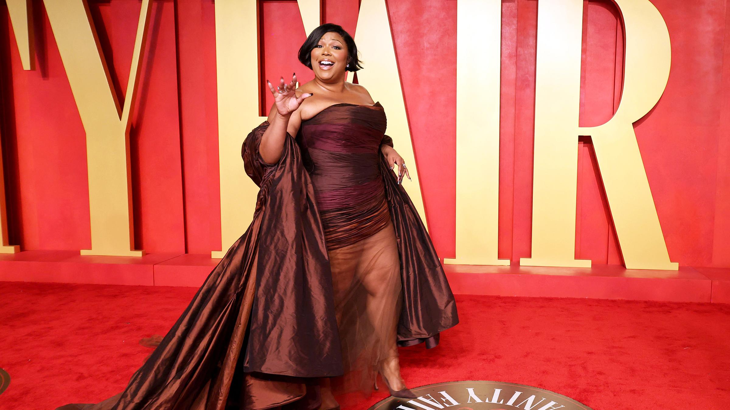 Sängerin Lizzo in rotem Kleid auf einem roten Teppich.
