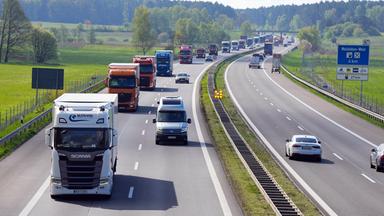 Eine lange Reihe von LKW fährt auf einer Autobahn.