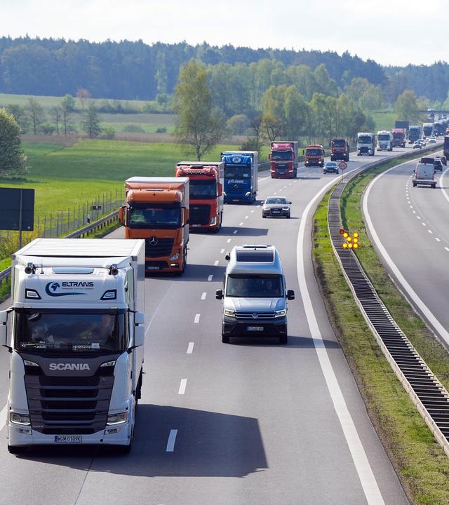 Eine lange Reihe von LKW fährt auf einer Autobahn.