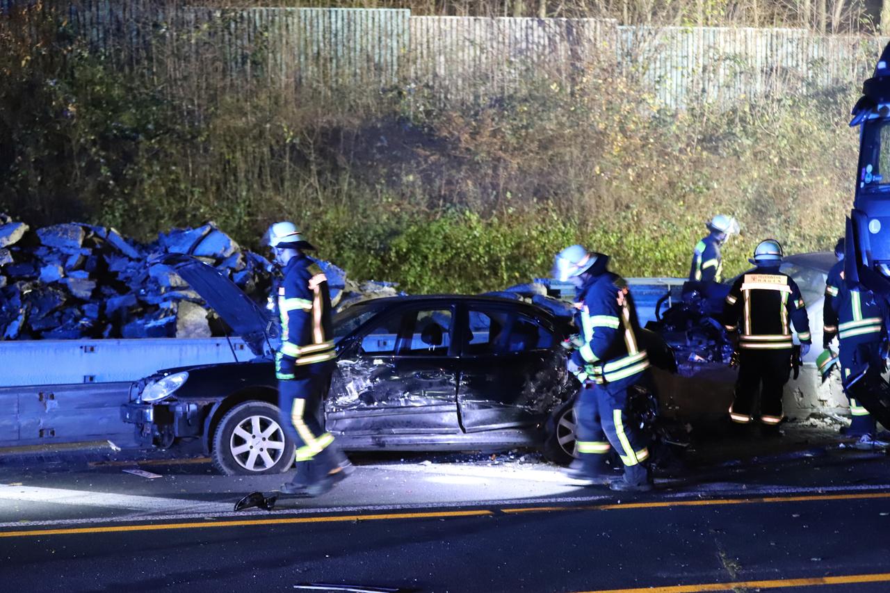 Nach Chaosfahrt auf Autobahnen in NRW: Einsatzkräfte der Feuerwehr stehen neben einem beschädigten Auto auf der A1.