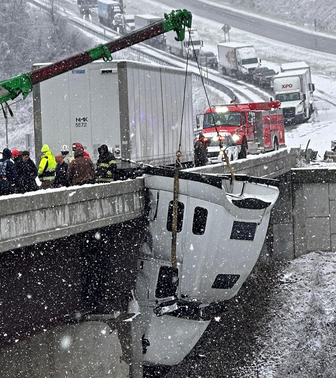 Einsatzkräfte in Virginia, die ein Lkw-Fahrerhaus bergen, das nach einem Unfall bei Glatteis an einer Brücke entlang der U.S. Route 35 hing