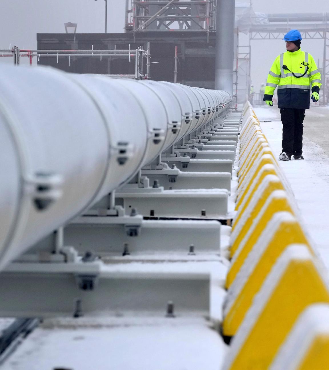 Ein Arbeiter geht an einer Gasleitung vorbei, die die schwimmende Speicher- und Regasifizierungseinheit (FSRU) „Hoegh Esperanza“ mit dem Festland verbindet.