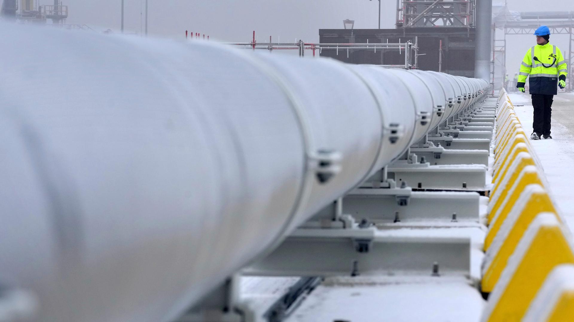 Ein Arbeiter geht an einer Gasleitung vorbei, die die schwimmende Speicher- und Regasifizierungseinheit (FSRU) „Hoegh Esperanza“ mit dem Festland verbindet.