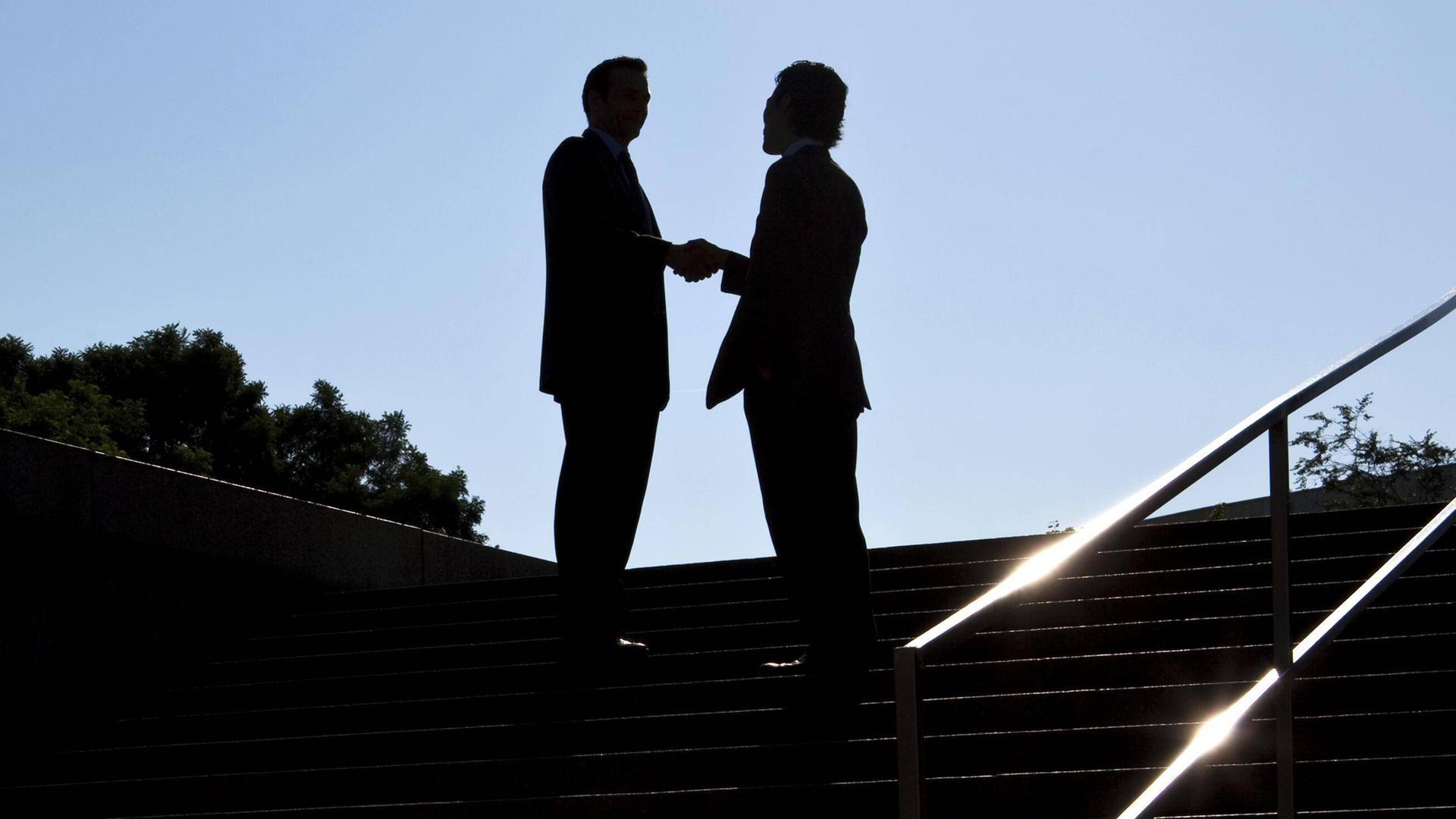 Zwei nicht zu erkennende Personen geben sich die Hand.