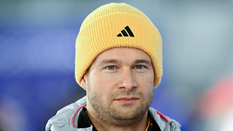 Der deutsche Bob-Pilot Johannes Lochner mit gelber Mütze und ernstem Blick