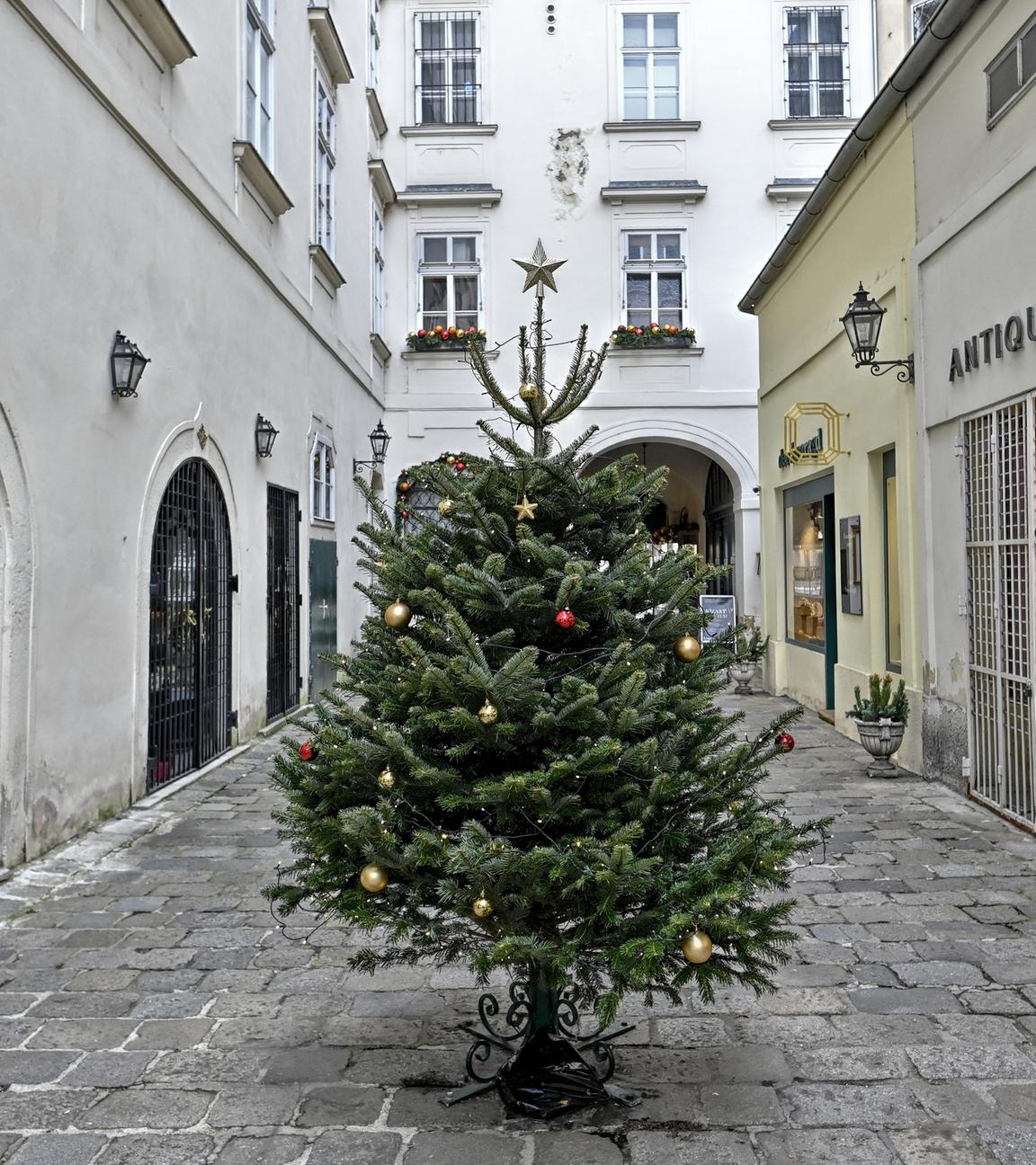 Tannenbaum in menschenleerem Innenhof, die umliegenden Geschäfte sind zu 