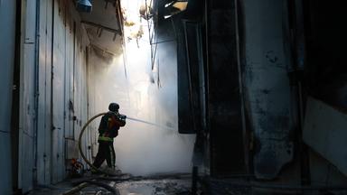 Archiv:  Ein Feuerwehrmann löscht einen Brand im Zentralmarkt von Saporischschja nach einem russischen Angriff. 