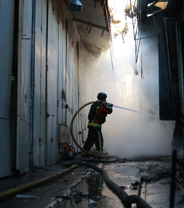 Archiv:  Ein Feuerwehrmann löscht einen Brand im Zentralmarkt von Saporischschja nach einem russischen Angriff. 