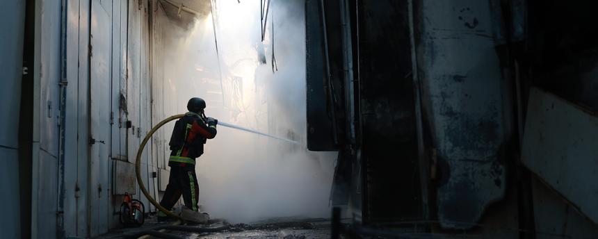 Archiv:  Ein Feuerwehrmann löscht einen Brand im Zentralmarkt von Saporischschja nach einem russischen Angriff. 