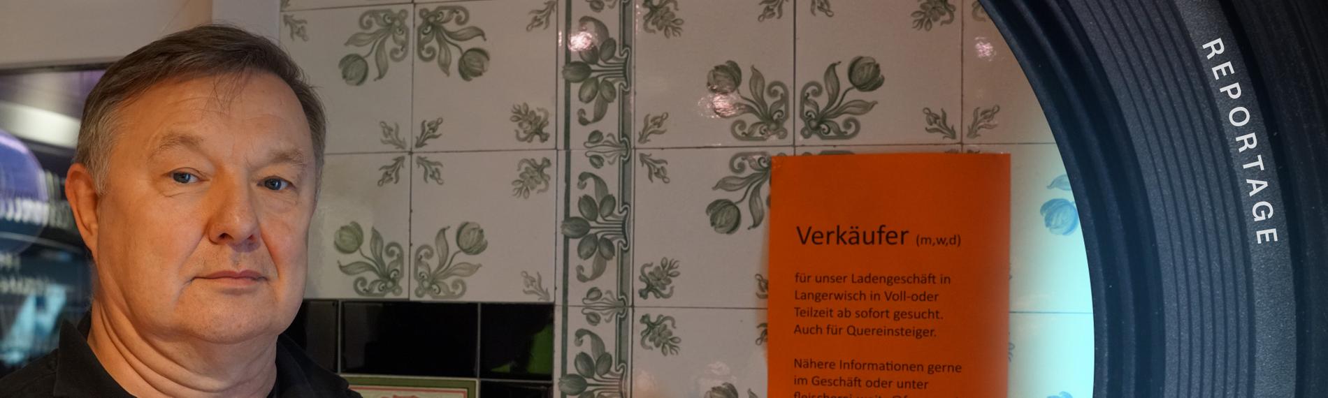 Metzger Volkmar Woite  zeigt auf ein orangenes Plakat rechts.