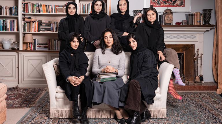 Sieben schwarz gekleidete Frauen, von denen mehrere ein Kopftuch tragen, sitzen in einem Sessel, bzw. stehen dahinter für ein Gruppenfoto.