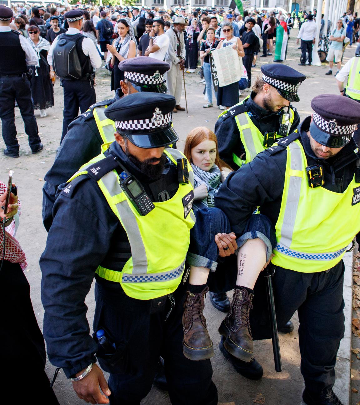 Polizeibeamte führen einen festgenommenen Anhänger von Palestine Action ab, der an einer Massenkundgebung teilgenommen hatte, die von der Gruppe „Defend Our Juries“ im Rahmen ihrer Kampagne zur Aufhebung des Verbots von Palestine Action auf dem Parliament Square in London, Großbritannien, am 9. August 2025 organisiert worden war.