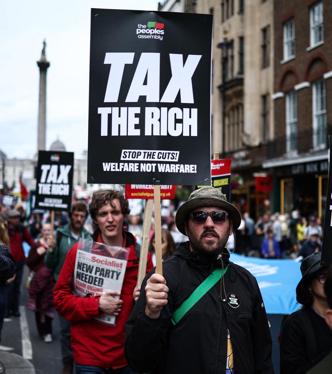 Ein Demonstrant hält ein schild mit der Aufschrift "TAX THE RICH"