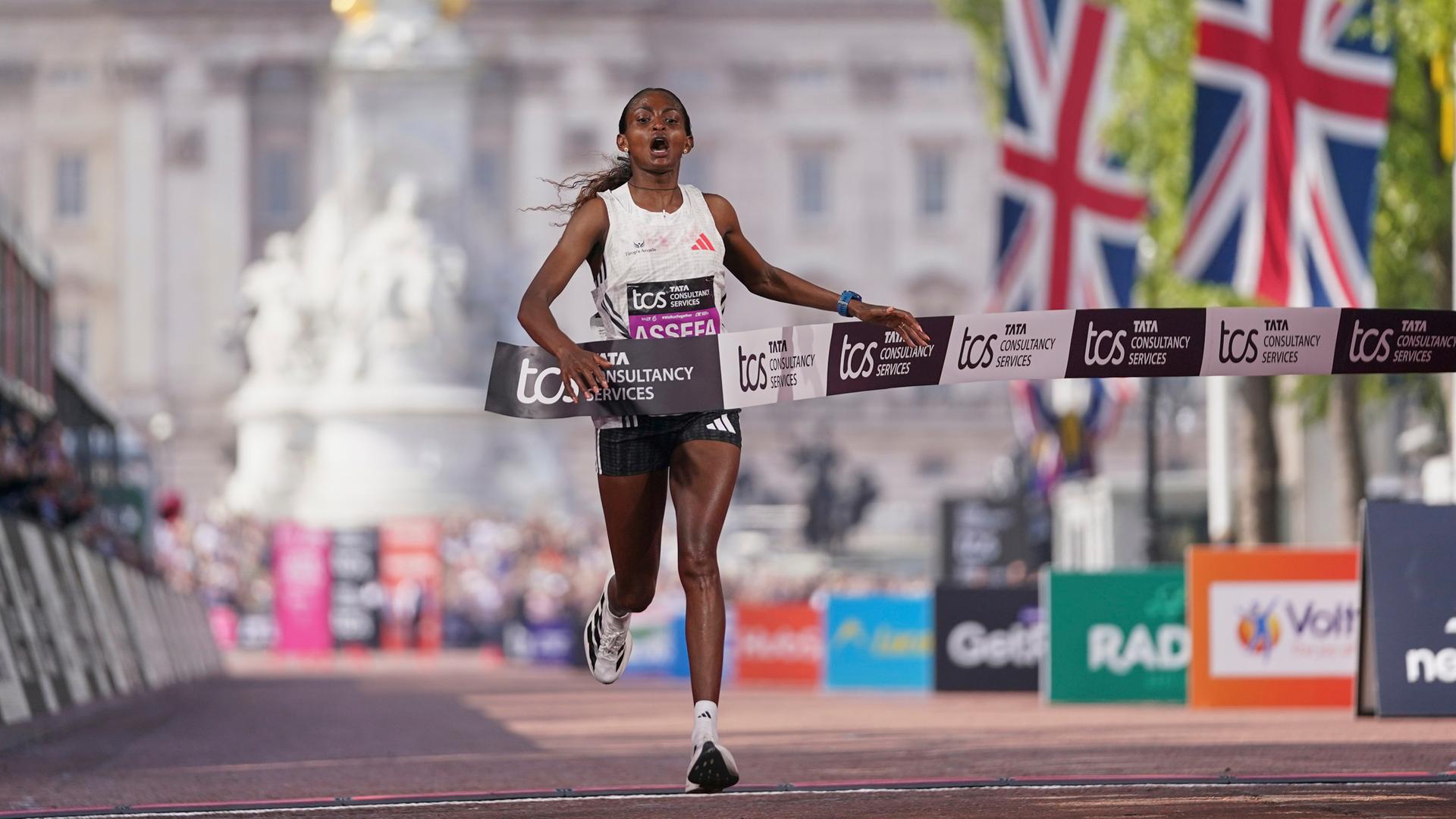 Großbritannien, London: Tigst Assefa (Äthiopien) überquert die Ziellinie beim London Marathon.