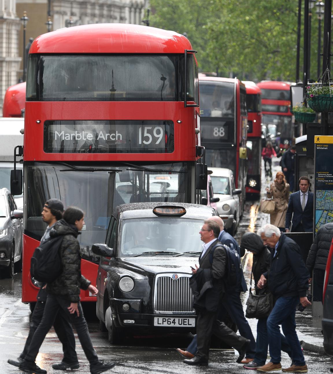Fußgänger laufen über eine vielbefahrene Straße in London.
