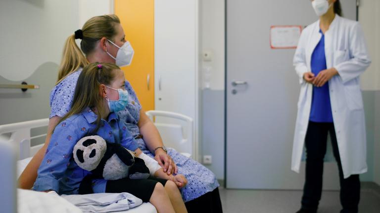 Ein Mädchen, das an Long Covid erkrankt ist, und seine Mutter sprechen mit einer Ärztin