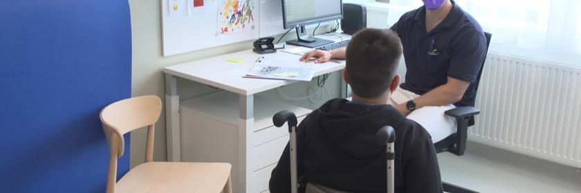 Junge im Rollstuhl spricht mit Kinderarzt
