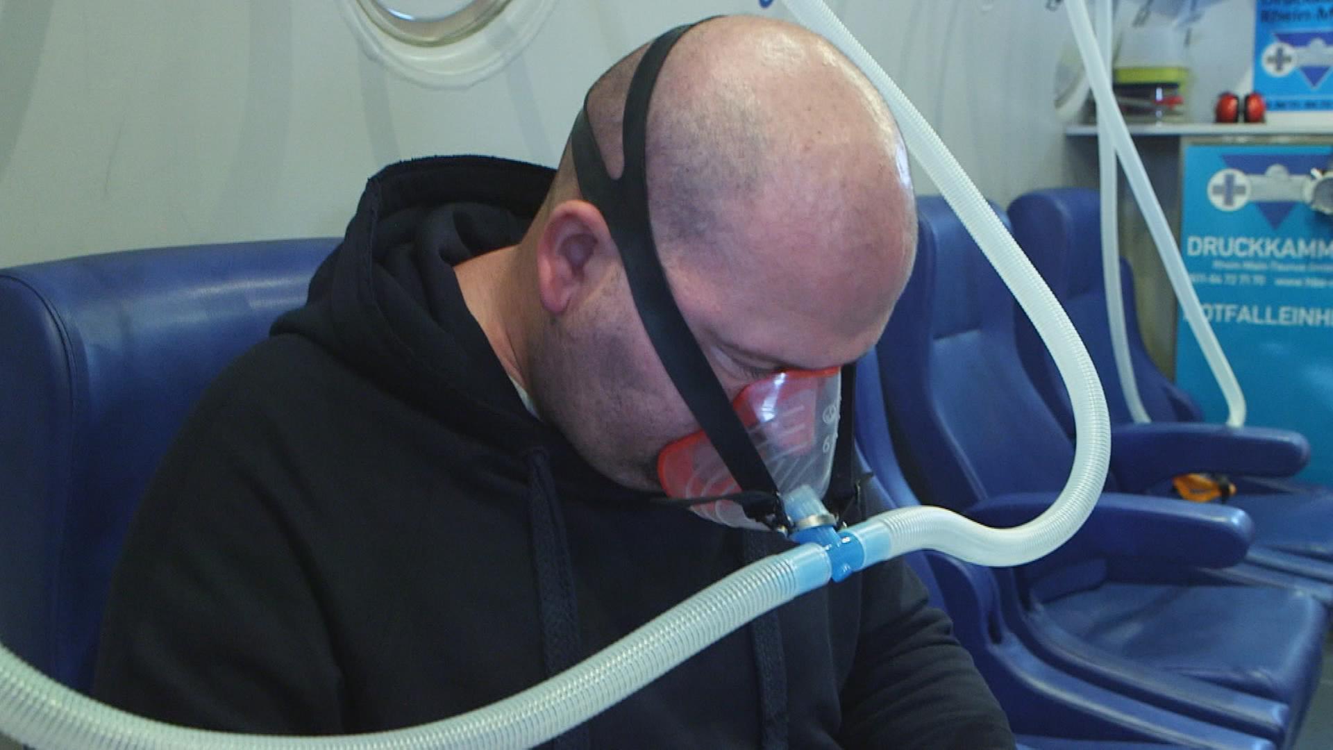 Long-Covid-Patient mit Atemmaske bei Therapie in Überdruckkammer
