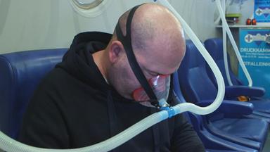 Long-Covid-Patient mit Atemmaske bei Therapie in Überdruckkammer