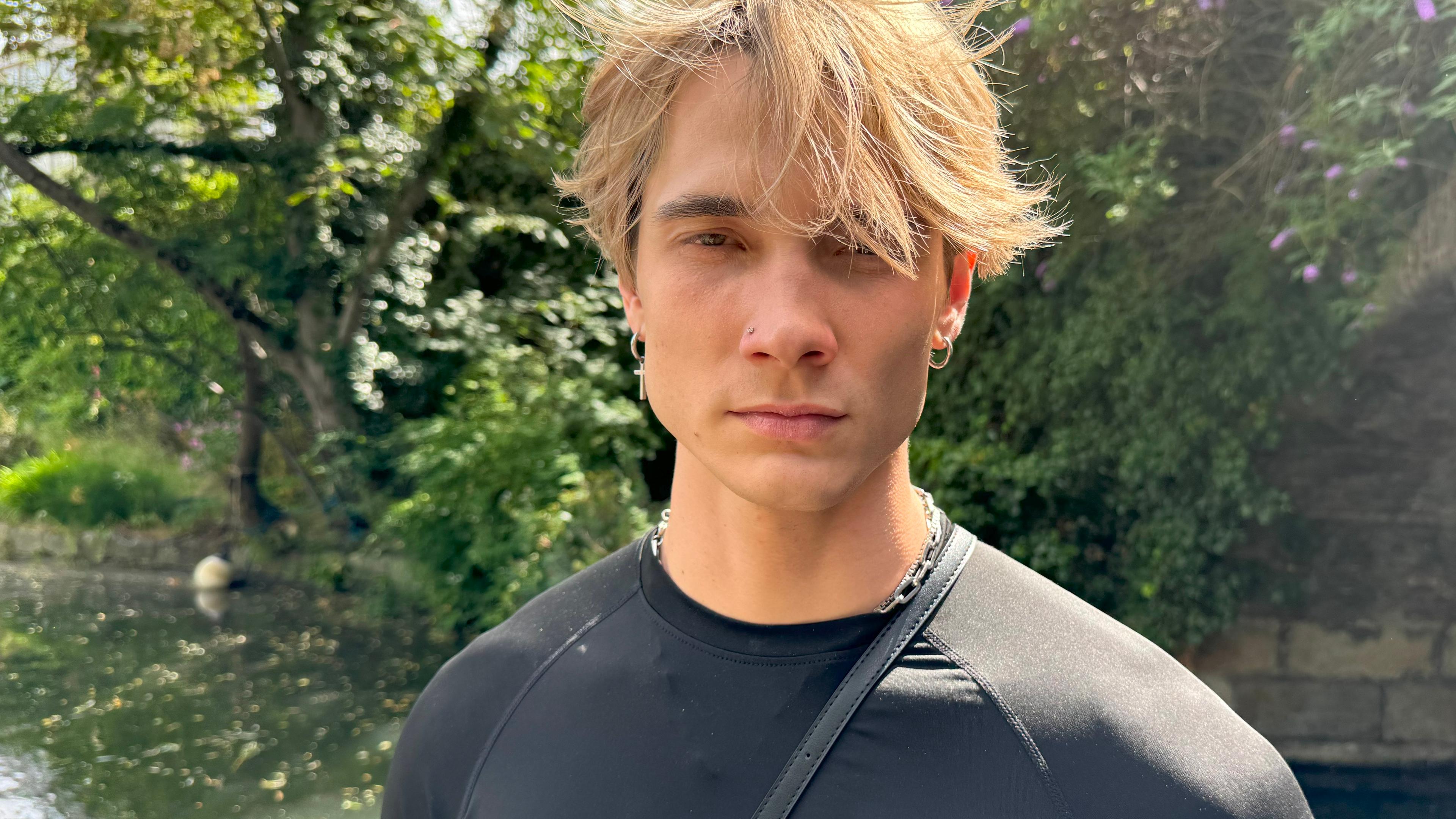 Portraitaufnahme: Austin Wayne steht vor einem See und schaut in die Kamera. Er hat blonde Haare und eine ausgeprägte Kiefermuskulatur.