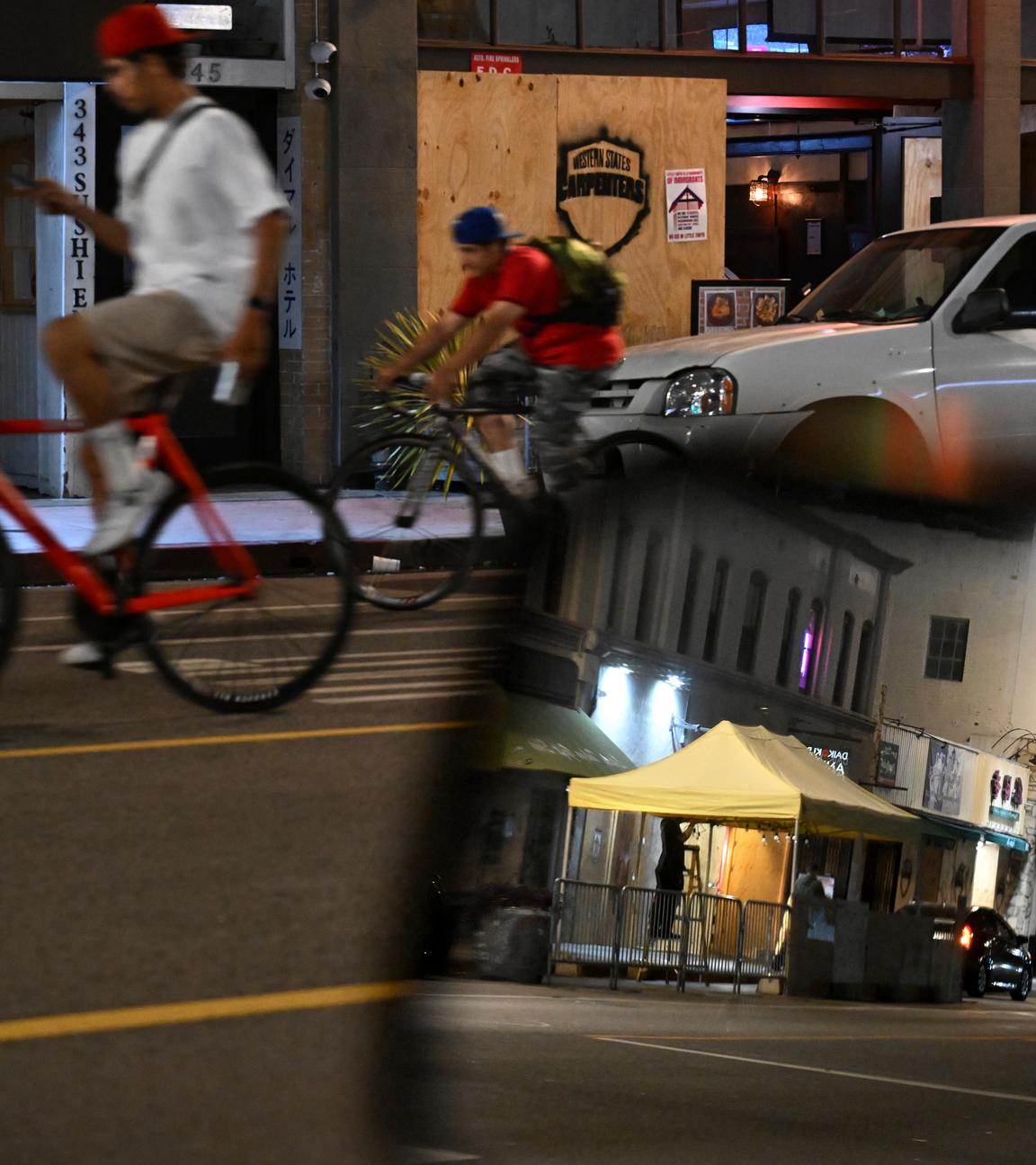 Fahrradfahrer fahren am Dienstag, den 17. Juni 2025, in Los Angeles an verrammelten Geschäften entlang der 1st St. in Little Tokyo vorbei.