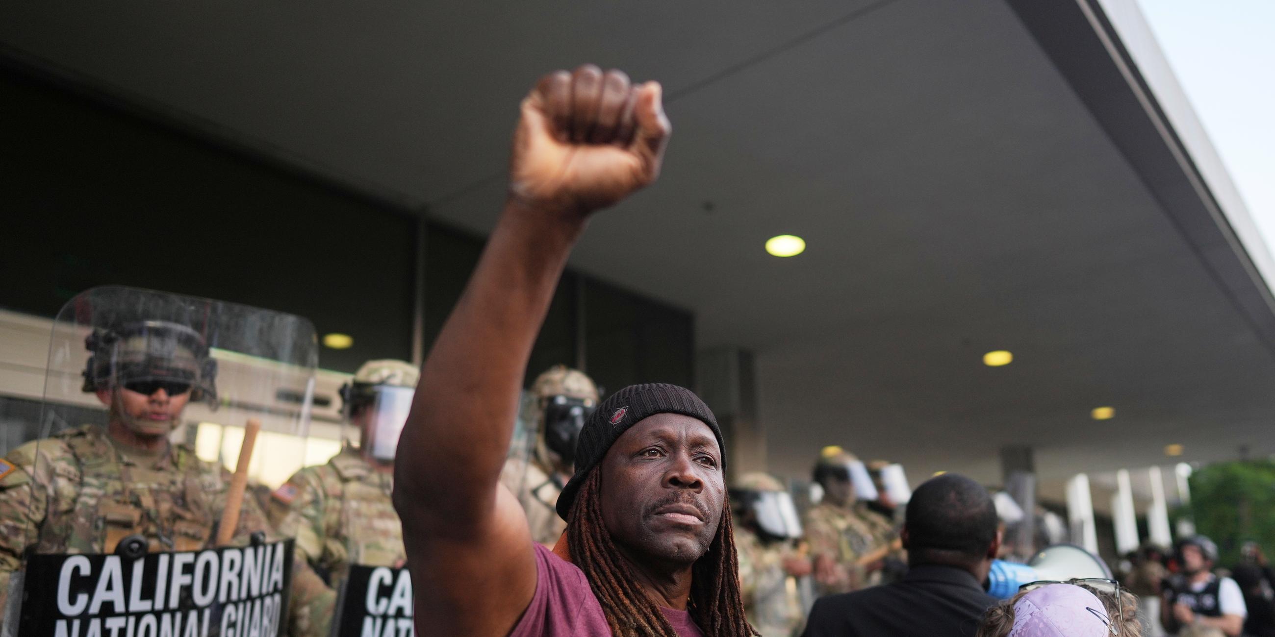 A man raises his fist as California National Guardsmen look on