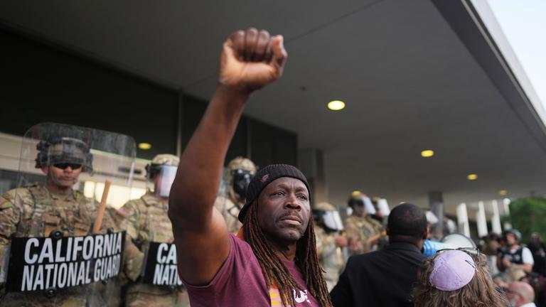 A man raises his fist as California National Guardsmen look on