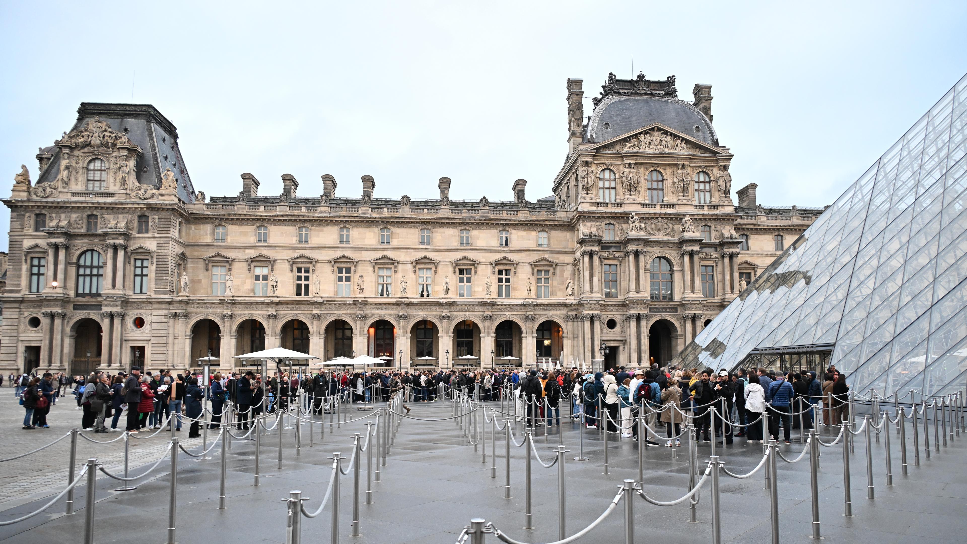 Menschen stehen Schlange, um das Louvre-Museum zu betreten, das nach dem Juwelenraub vom Sonntag (19.10.2025) für den Tag geschlossen bleibt.