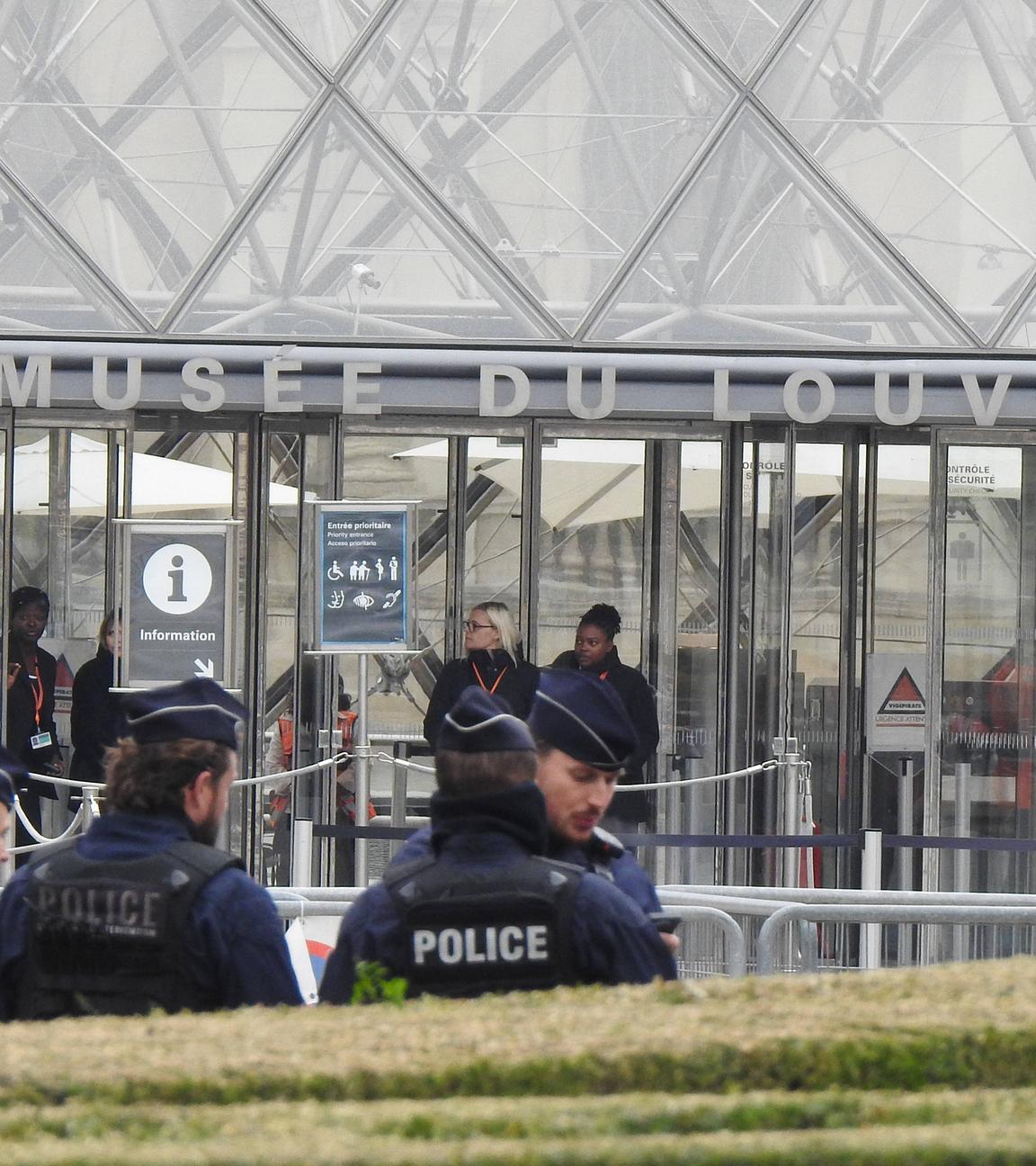 Man sieht Polizeibamte, die vor dem Louvre stehen und den Zugang sperren
