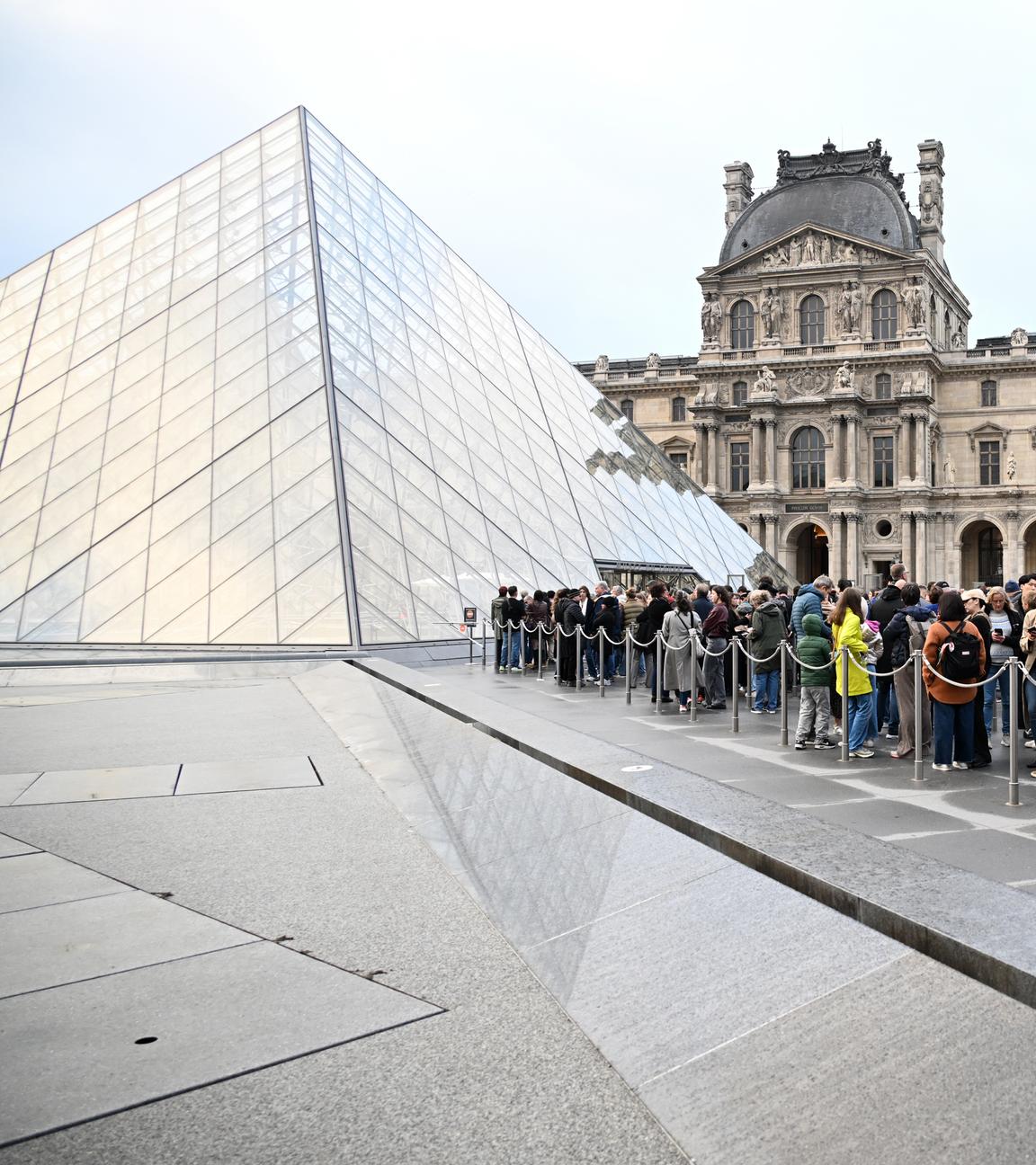 In Paris stehen Menschen im Hof der Louvre-Pyramide Schlange.