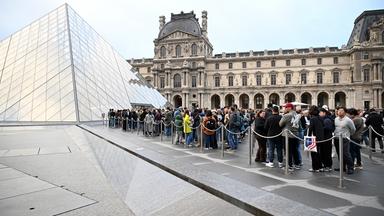 In Paris stehen Menschen im Hof der Louvre-Pyramide Schlange.