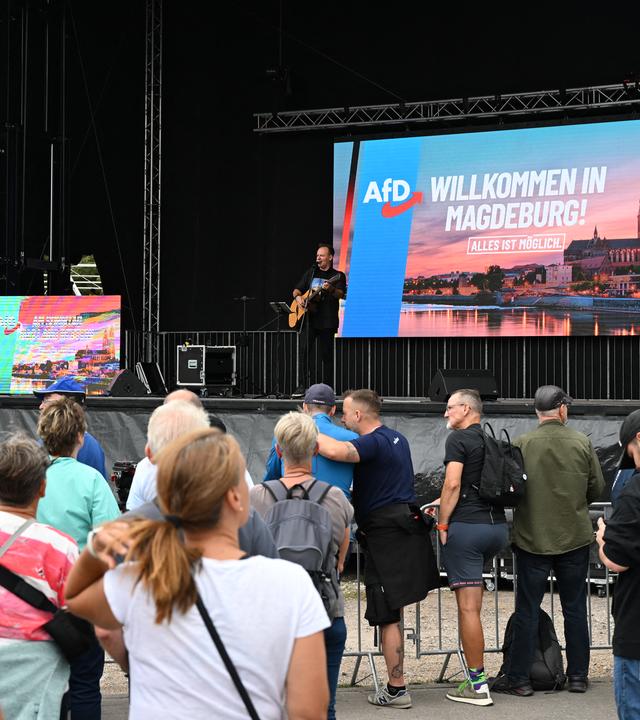 Besucher stehen vor der Bühne eines AfD-Familienfests in Magdeburg, während ein Musiker auftritt. den Umfragewerten zufolge wird die AfD mit Abstand die stärkste Kraft.